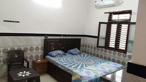 a bedroom with a bed and a chair and a window at Vallabh Kunj Sewa Sadan in Govardhan