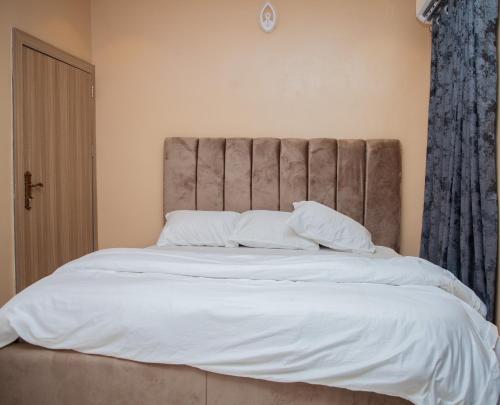 a bedroom with a large bed with white sheets and pillows at Radores Apartment in Ayobo
