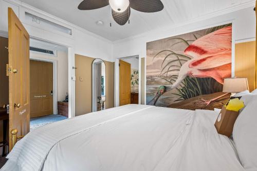 a bedroom with a white bed with a painting on the wall at Old Carrabelle Hotel Magnolia Suite in Carrabelle