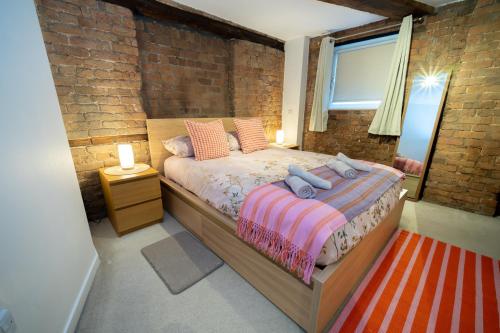 a bedroom with a bed and a brick wall at Rustic 2BR Loft Exposed Brick & Beams in Liverpool