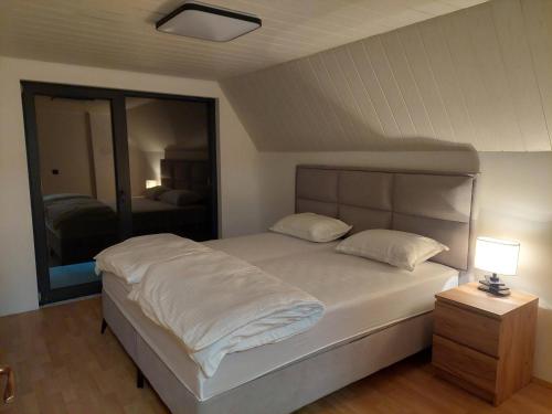 a bedroom with a white bed with a night stand and a lamp at Kuca za odmor Moj Mir in Kalesija