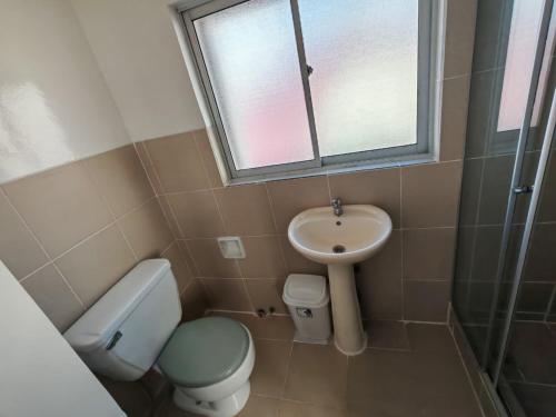 a bathroom with a toilet and a sink and a window at York Hostel in La Paz