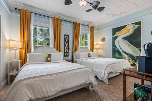 a bedroom with two beds and a painting of a bird at Old Carrabelle Hotel Captains Quarters Suite in Carrabelle