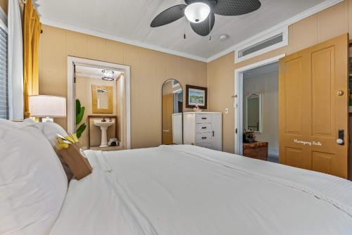 a bedroom with a large white bed with a ceiling fan at Old Carrabelle Hotel Hemingway Suite in Carrabelle