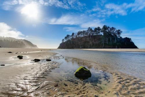 a beach with a rock in the water at 2nd Tee at Neskowin Village in Neskowin