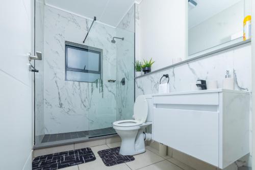 a bathroom with a shower and a toilet and a sink at Fynbos Lifestyle Estate - One Bed Apartment in Cape Town