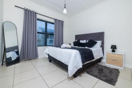 a bedroom with a large bed and a mirror at Fynbos Lifestyle Estate - One Bed Apartment in Cape Town