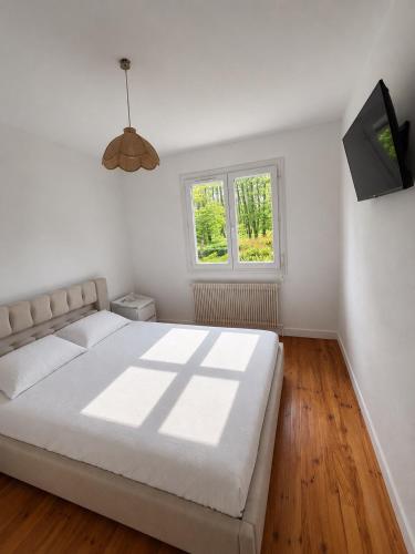 a white bedroom with a bed and a window at maison moderne en face de la mer in Arès