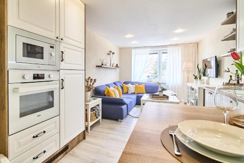 a kitchen and living room with a blue couch at Smart apartmány Prešov in Prešov