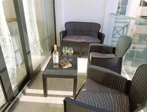 a balcony with two chairs and a table with wine glasses at Deluxe Arguineguin Beach in Arguineguín
