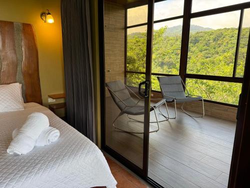a bedroom with a bed and a chair and a window at Rainbow Valley Lodge Costa Rica in Monteverde Costa Rica