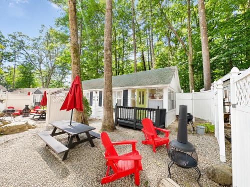 a backyard with red chairs and a grill and a house at Cottage 12 - King Bed Child Loft w Twin Private Bath Kitchenette Pets Allowed Fee applies in Wolfeboro