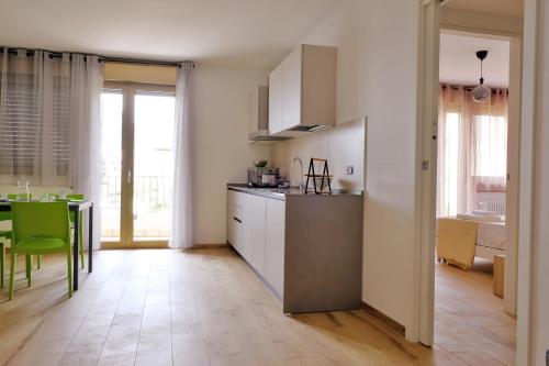 a kitchen with white cabinets and a table with green chairs at Le Mele - Alle 5 Torri in Mezzolombardo