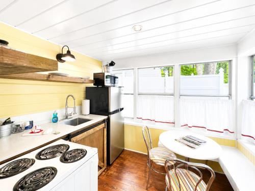 a kitchen with a stove top oven next to a table at Cottage 12 - King Bed Child Loft w Twin Private Bath Kitchenette Pets Allowed Fee applies in Wolfeboro