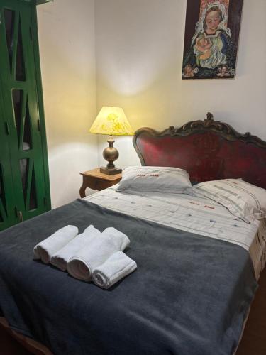 a bed with two folded towels on it with a lamp at Paraíso com piscina e lareira no centro in Serra Negra