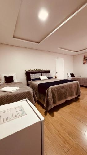 a room with two beds and a table in it at POUSADA DONATELLA Modernidade e conforto para noites tranquilas in Paranaguá