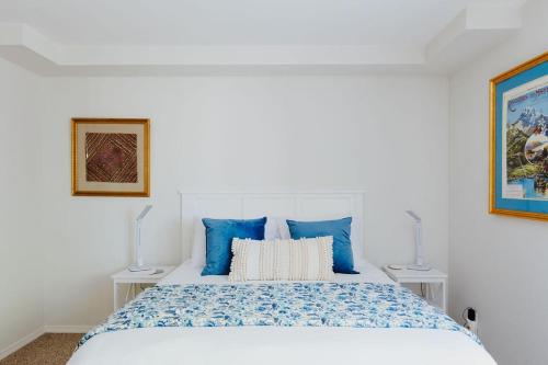 a white bedroom with a large bed with blue pillows at The Perch at Eagle Harbor in Bainbridge Island