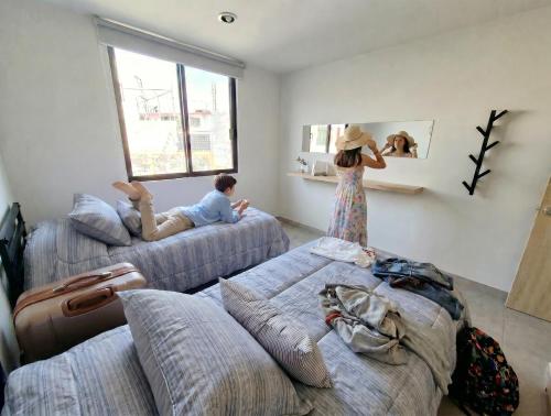 a woman standing in a room with two beds at Luminoso departamento cerca de bodas y jardines! in Atlixco