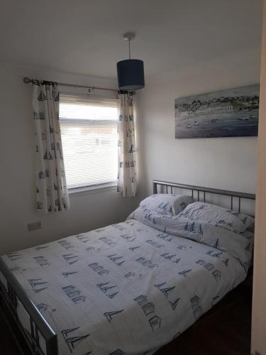 a bedroom with a bed with a comforter and a window at Sunrise 77 Sandown Bay Holiday Centre Generous Ferry Saving! in Sandown