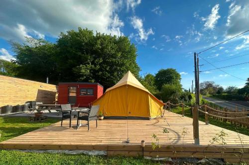 a tent and a table and chairs on a wooden deck at Ardennes Prestige Glamping in La Neuville-aux-Joûtes