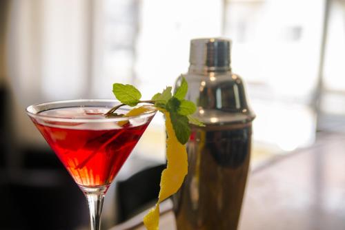 a red drink in a glass next to a bottle at Hotel Continental Luanda in Luanda