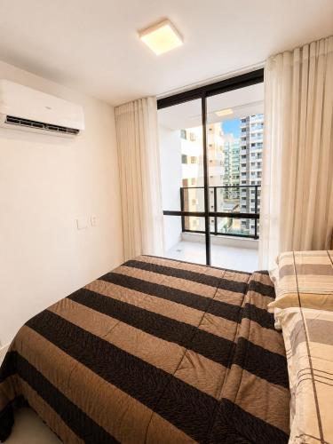 a bedroom with a bed and a large window at SkyHero Apê in Vila Velha