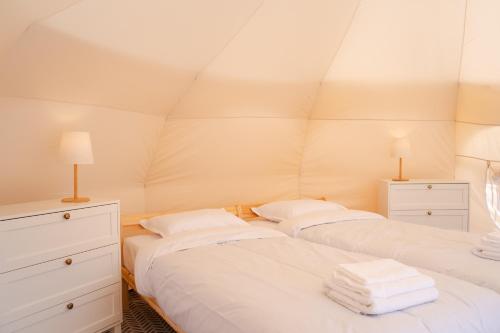 two twin beds in a room with a pyramid ceiling at Glamping Stolat in Stolat