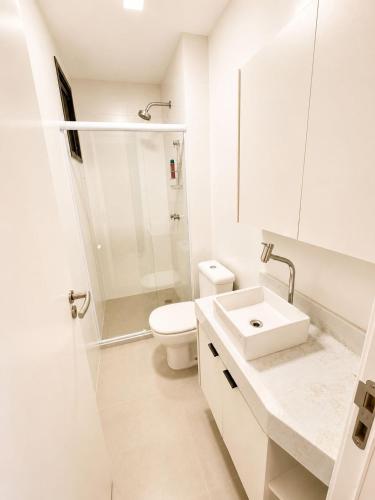 a white bathroom with a toilet and a sink at SkyHero Apê in Vila Velha