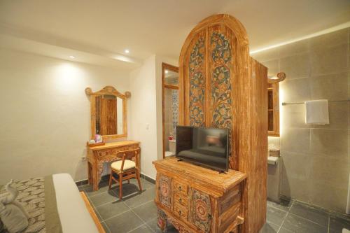 a bedroom with a tv and a bed and a mirror at The Alugara Suite & Spa in Tegalalang