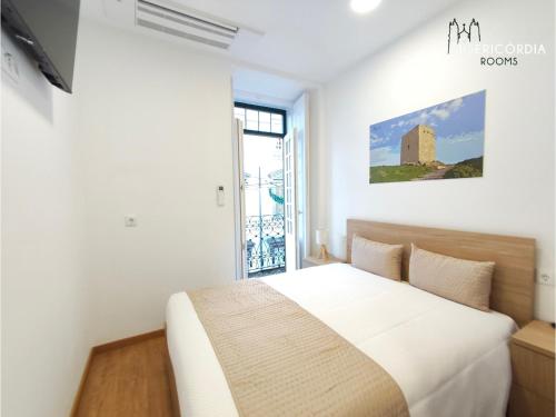 a white bedroom with a bed and a window at Misericórdia Rooms in Guarda