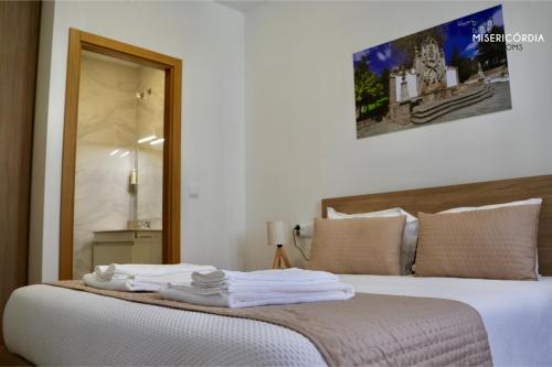 a bedroom with a bed with towels on it at Misericórdia Rooms in Guarda