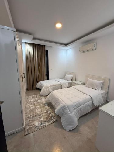 a bedroom with two beds and a sliding door at Prime Plaza Porto Towers Stay Hotel VIP in Ain Sokhna