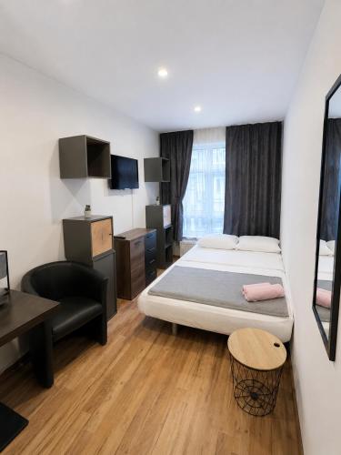 a bedroom with a bed and a desk and a chair at Pension Ksenija Hanau in Hanau am Main