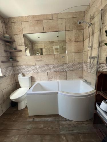 a bathroom with a tub and a toilet and a mirror at Summer Salt house in Morecambe