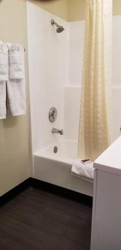 a bathroom with a shower and a white tub at Sierra Crossing Motel in Bloomington