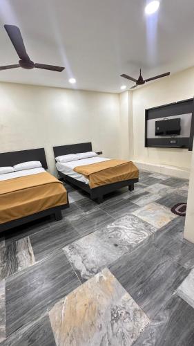 a room with two beds and a flat screen tv at Femina Residency in Kumbakonam