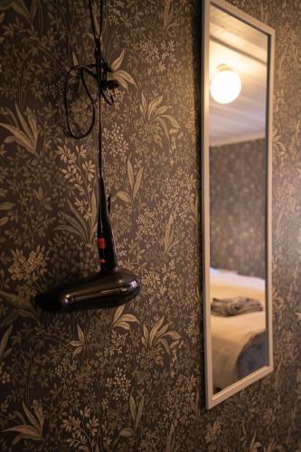 a vase on a wall with a mirror and a lamp at Gården in Östersolf