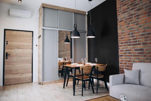 a dining room with a table and chairs and a brick wall at Apartament Centrum Żywiec - PILSKO in Żywiec