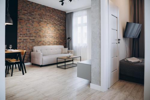 a living room with a white couch and a brick wall at Apartament Centrum Żywiec - PILSKO in Żywiec