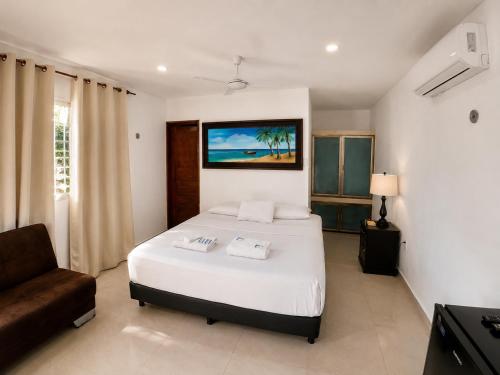 a bedroom with a large white bed and a couch at Villas Karalv in Bacalar