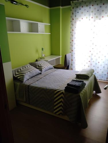 a bedroom with a bed with green walls and a window at Apartamento ROMA in Nájera