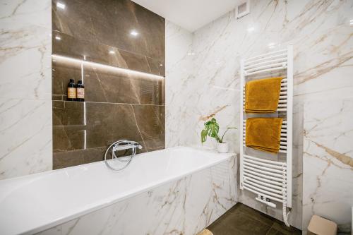 a bathroom with a white tub and marble walls at Turistka Loft in Kutná Hora