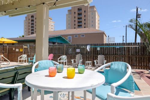 a white table with three colorful glasses on a patio at House of Neptune Steps from the sea and private pool in South Padre Island