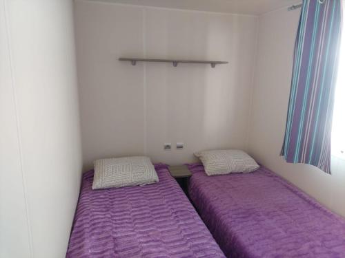 two beds in a small room with purple sheets at Cantinho da Rosa in Pataias