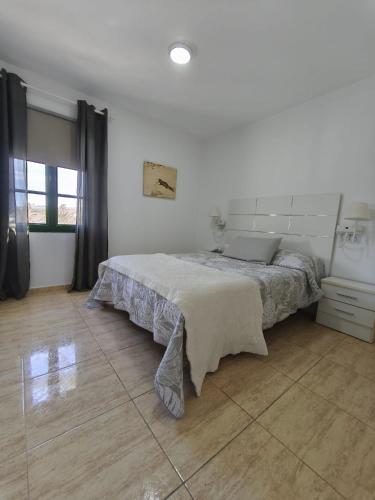 a white bedroom with a bed and a wooden floor at Santa Úrsula 66 in Costa Calma