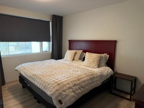 a bedroom with a large bed with a large window at Hugleikshus in Hvolsvöllur