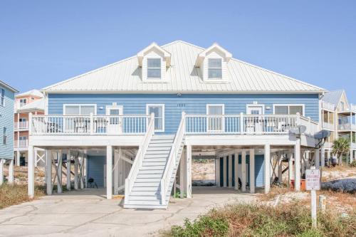 a large blue house with a white deck at Dandy Sandy Sleeps 24 - Pets - Pools - Hot Tubs in Gulf Shores