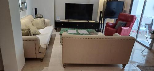 a living room with a couch and two chairs and a tv at Ville n4 in Sidi Daoud