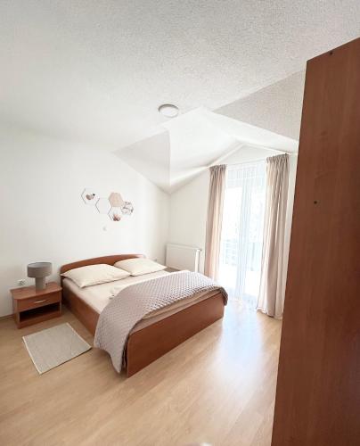 a white bedroom with a bed and a large window at Kovač Home in Posušje