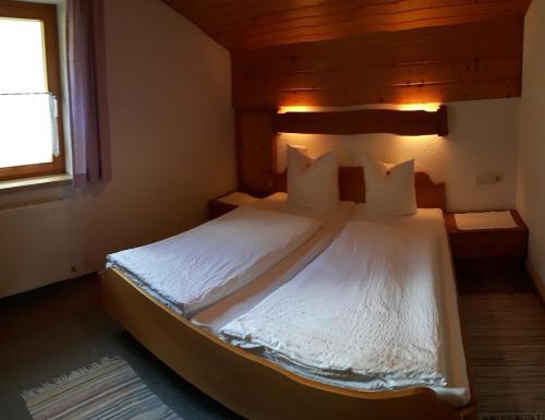 a bedroom with a bed with white sheets and a window at Apartmenthaus Immler in Gaschurn